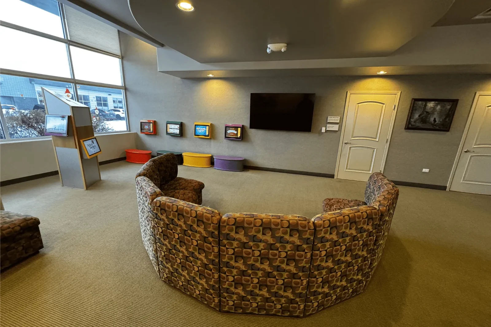 Children's waiting area with a curved couch and wall-mounted television.
