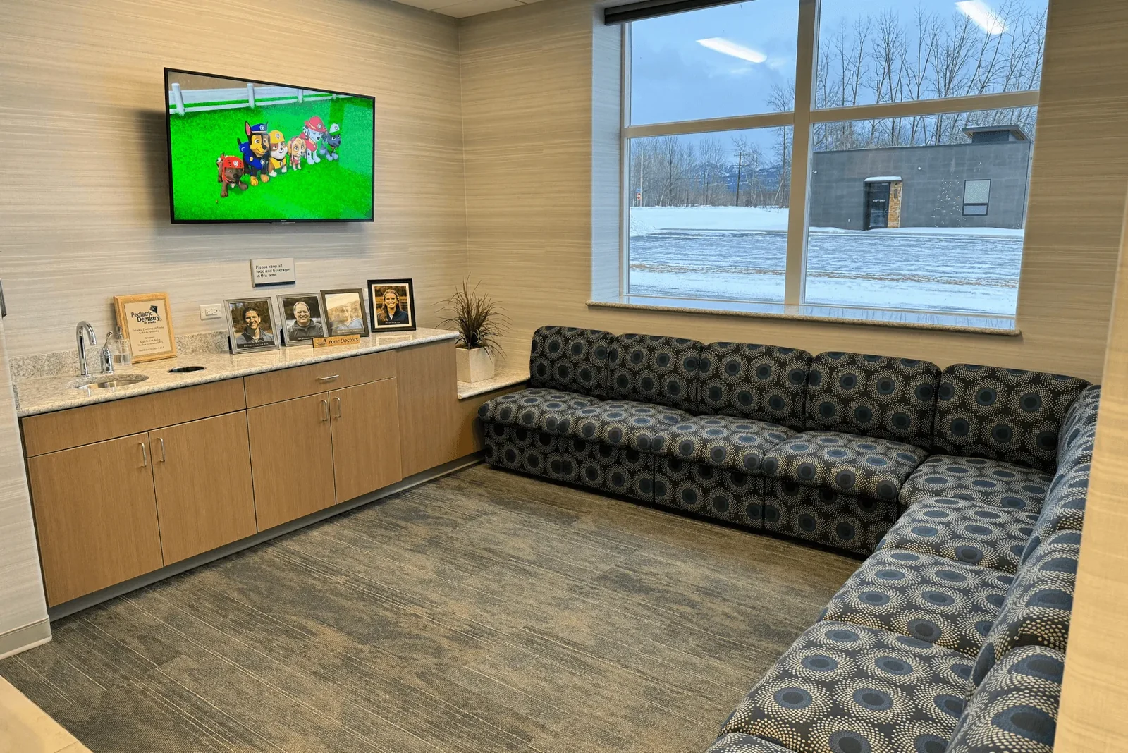 Waiting area with seating, a large window, and a wall-mounted television.